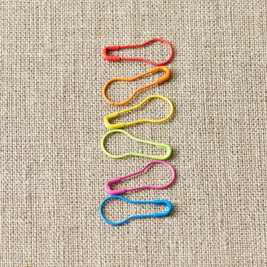 Colorful opening stitch markers on a light gray surface. 