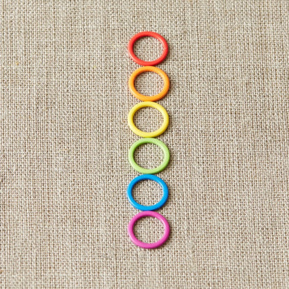 Colorful ring stitch markers on a light gray background. 