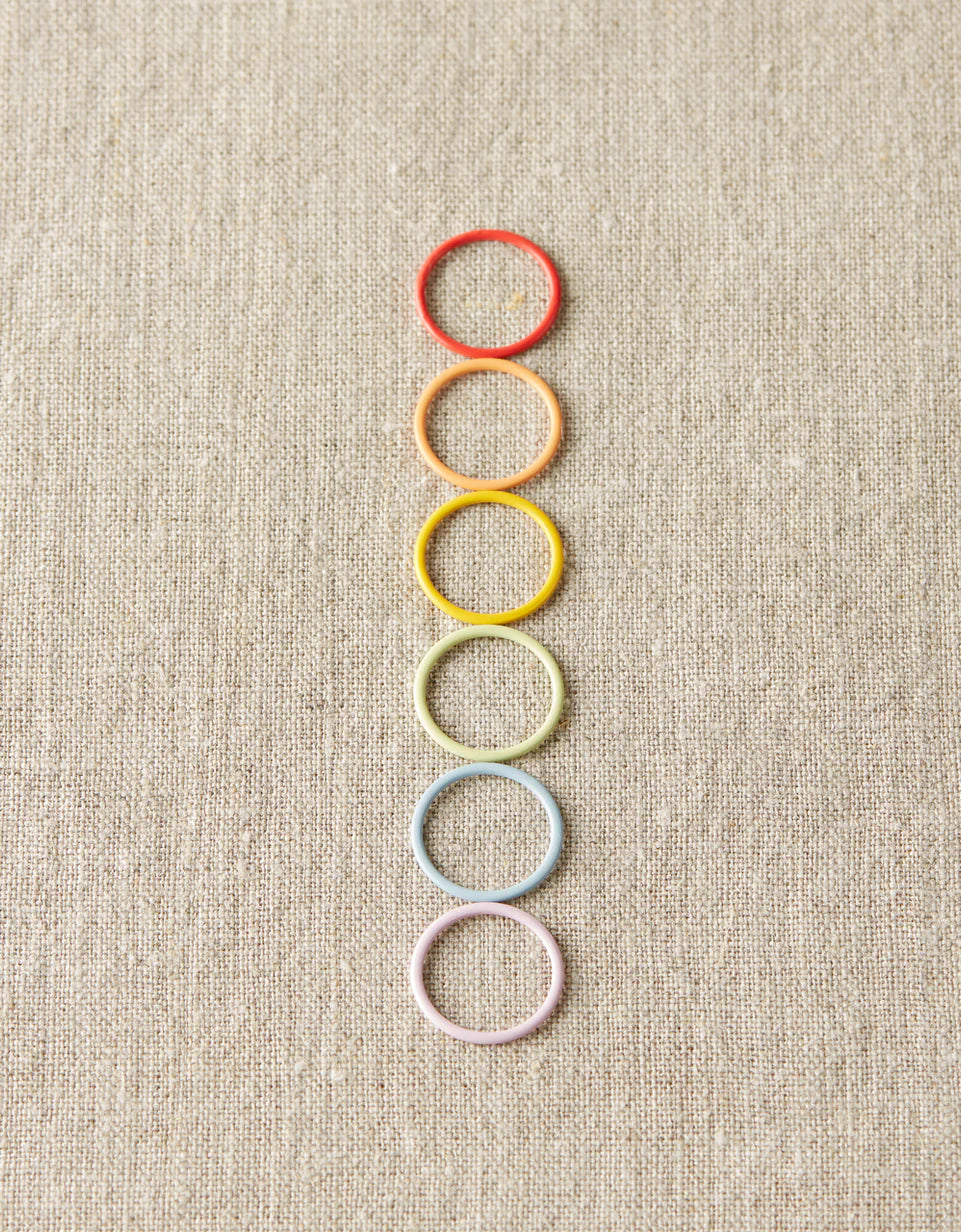 Rainbow of pastel round markers on a gray background. 