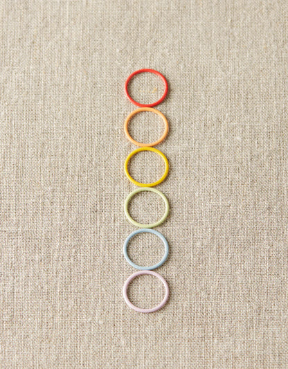 Rainbow of pastel round markers on a gray background. 