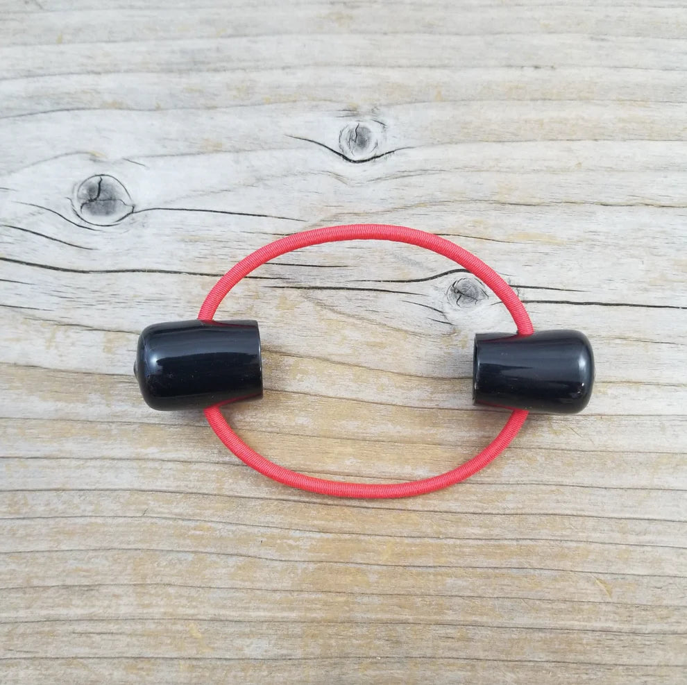 Double point knitting needle holder with two black plastic endcaps, connected by red elastic. 