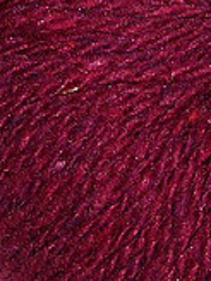 Close up on a dark burgundy tweed ball of Queensland Kathmandu Aran yarn. 