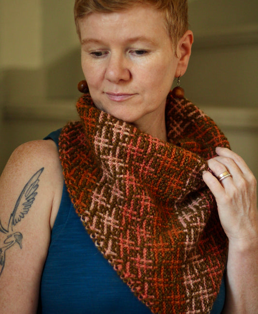 Designer Gudrun Johnston wearing a handknit mosaic “Cloud Drift” cowl in shades of pink. 