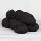 Three skeins of dark brown Fibre Co. Arranmore Light yarn. 