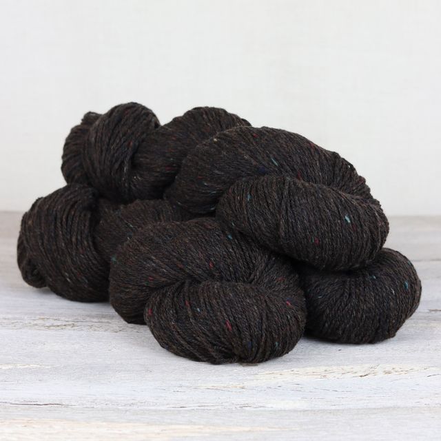 Three skeins of dark brown Fibre Co. Arranmore Light yarn. 