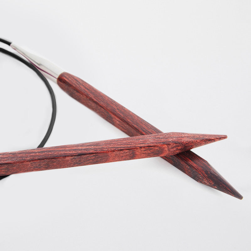 Close up on brown circular needles connected by a black cord. 