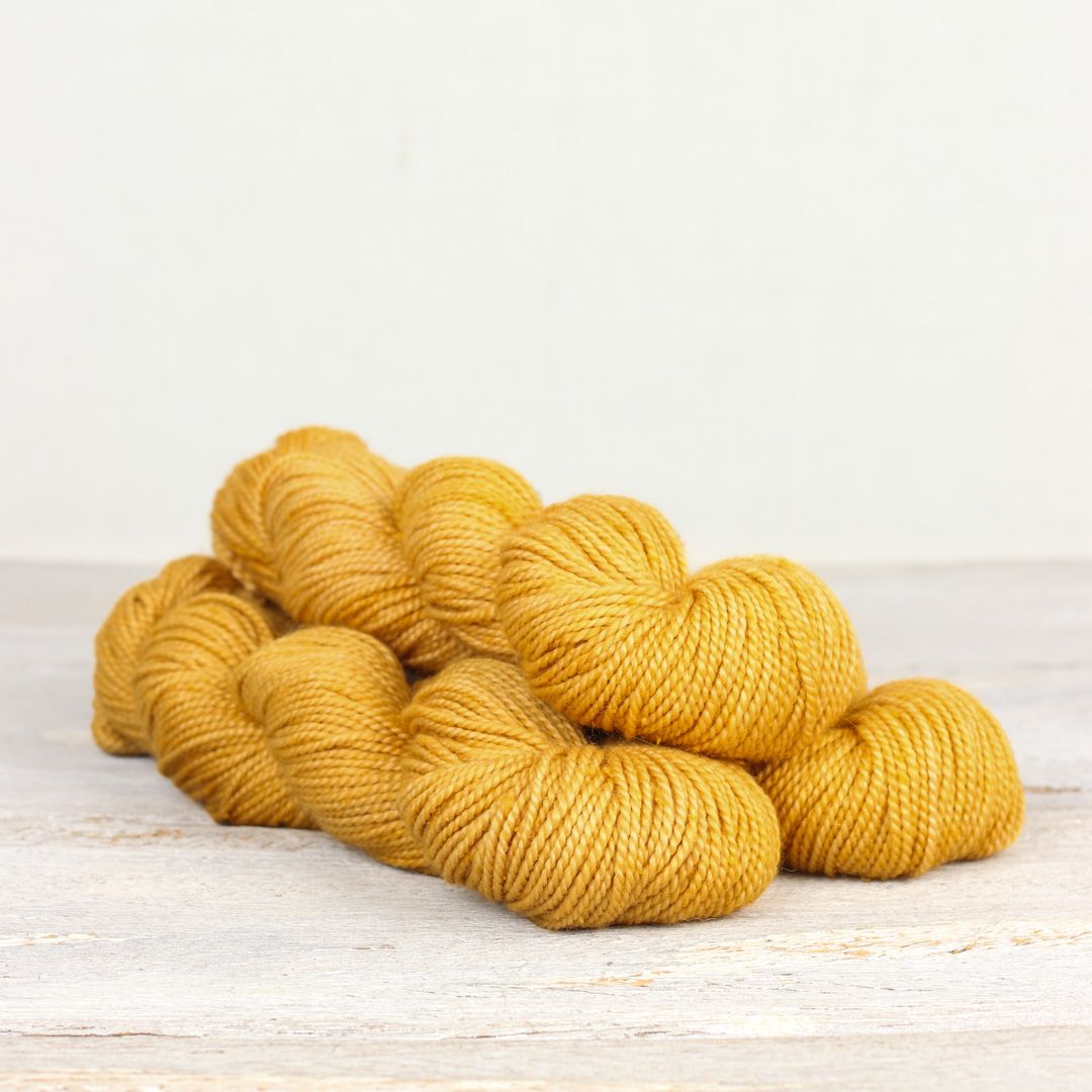 3 skeins of bright yellow Fibre Co. Acadia yarn. 