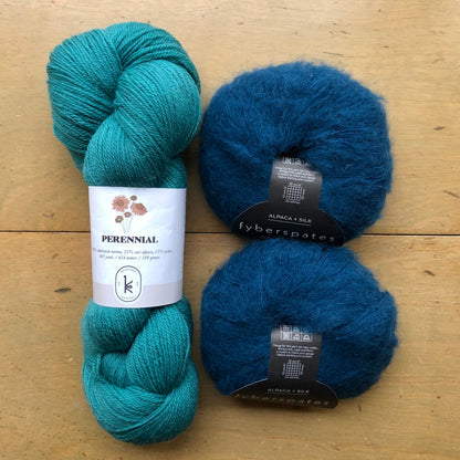 The contents of an "Oslo Hat" Kit - Hillsborough Yarn Shop edition are laid out on a wooden surface: one skein of Kelbourne Woolens Perennial in Teal Green and two balls of Fyberspates Cumulus in Moonlight. 